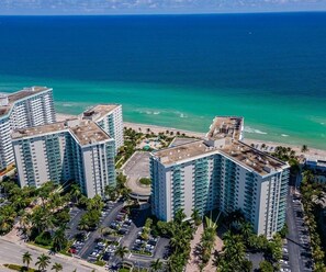Hotel alto com várias varandas com vista para uma praia e oceano.