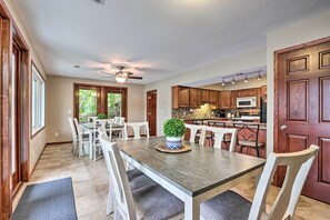 Une cuisine spacieuse avec des meubles de rangement en bois, une table à manger avec des chaises et un ventilateur de plafond.