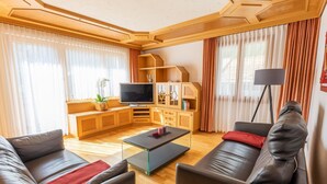 Ein modernes Wohnzimmer mit Sofa, Couchtisch, Fernseher und Schrank.
