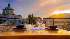 A table with a wine glass and bowls on a terrace with a view of a church and sunset. - Nukari Quinta Boutique (Jala)