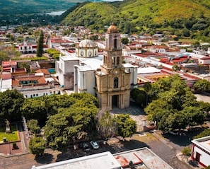 An aerial view of a town with a prominent church featuring a bell tower, surrounded by residential buildings and lush greenery.