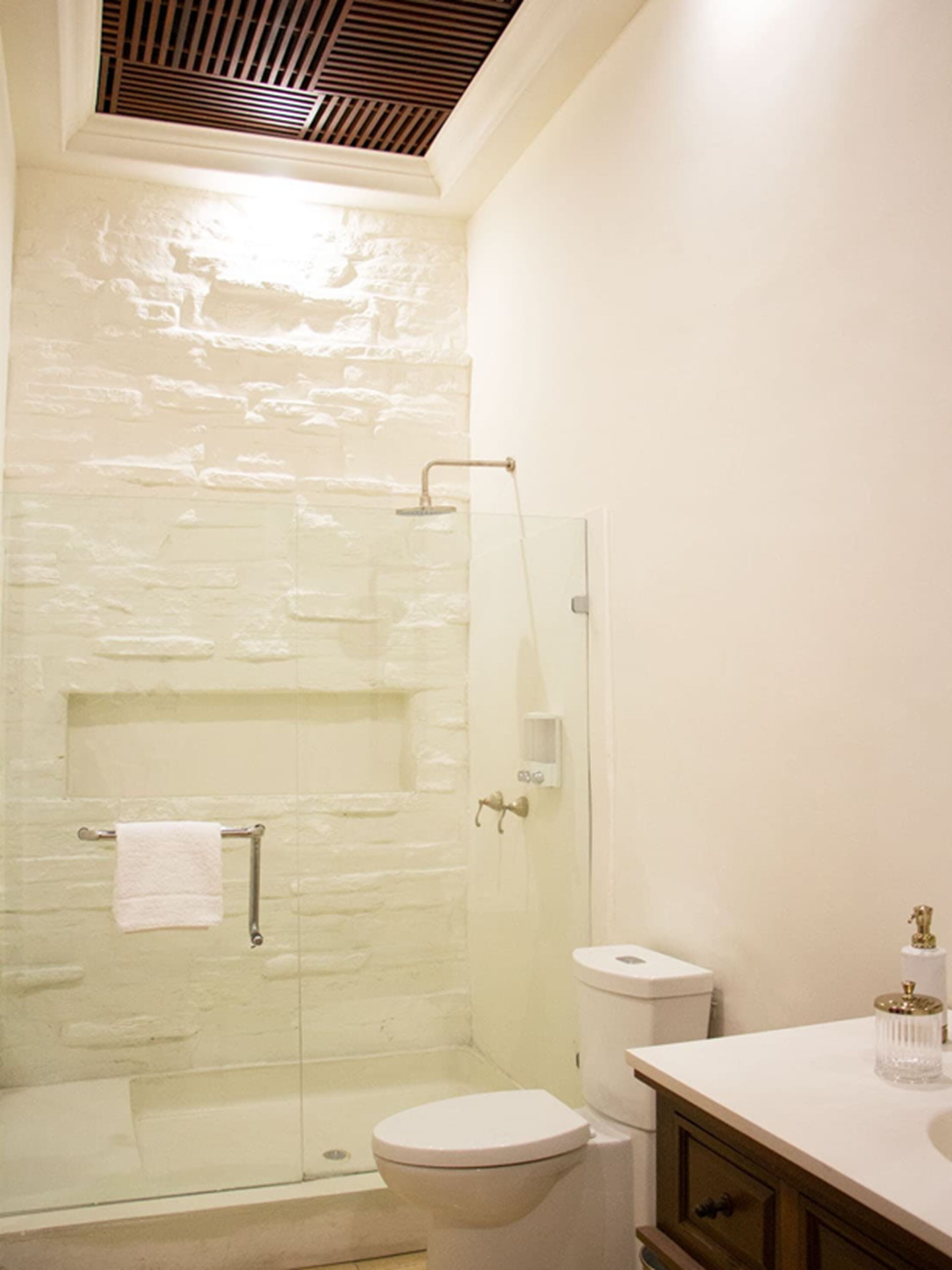 Un baño con cabina de ducha de vidrio, inodoro y tocador con espejo.