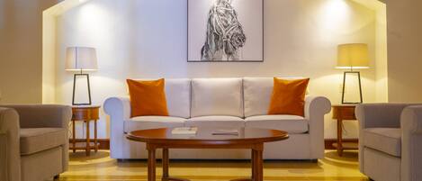 A modern living room with a white sofa, two armchairs, a wooden coffee table, and two floor lamps.
