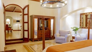 A hotel room with a bed, a wardrobe, a sitting area with a chair, a small table, and a mirror. - Nukari Quinta Boutique (Jala)