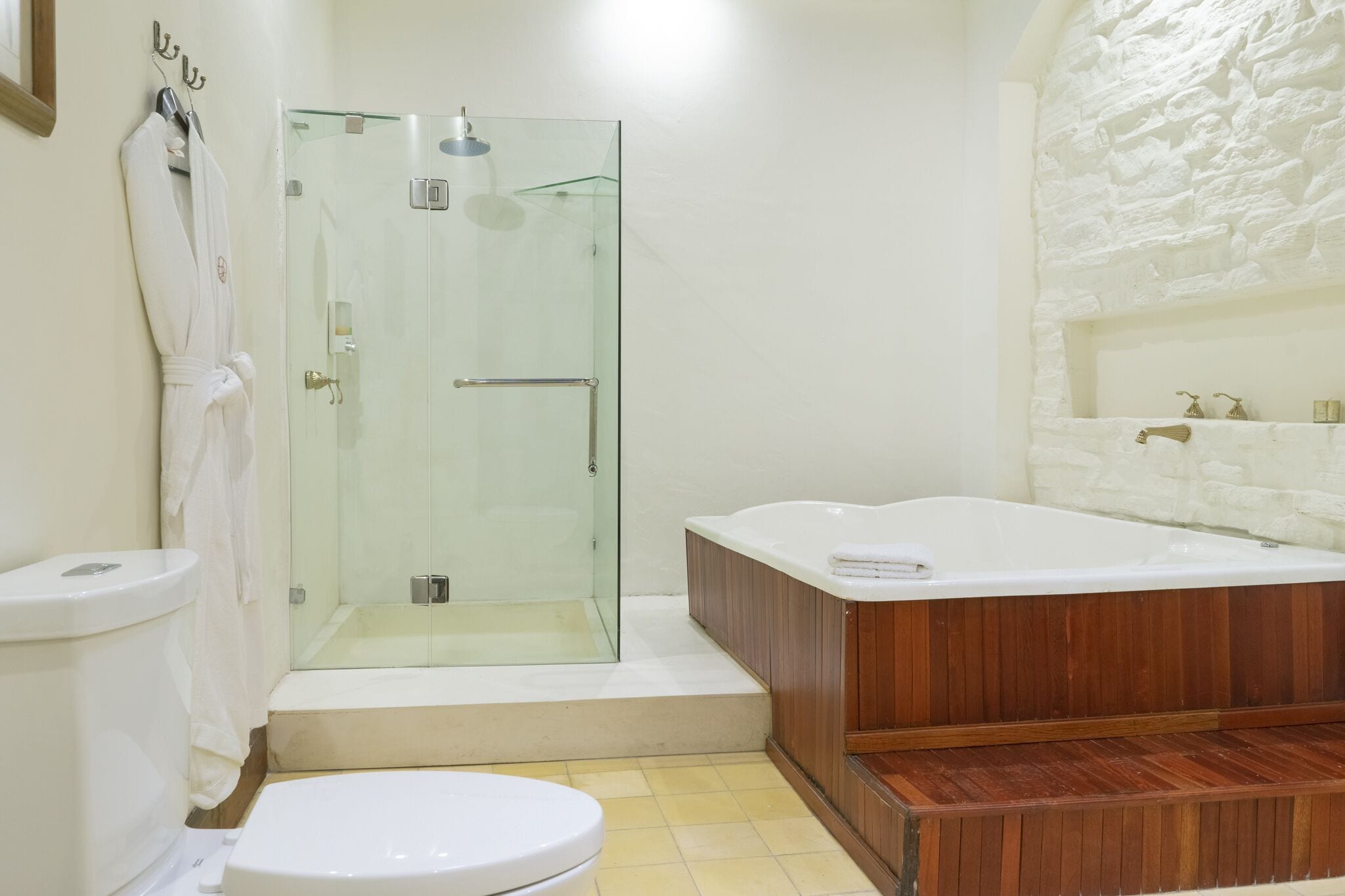 A modern bathroom with a glass-enclosed shower, a wooden bathtub, and a white toilet.