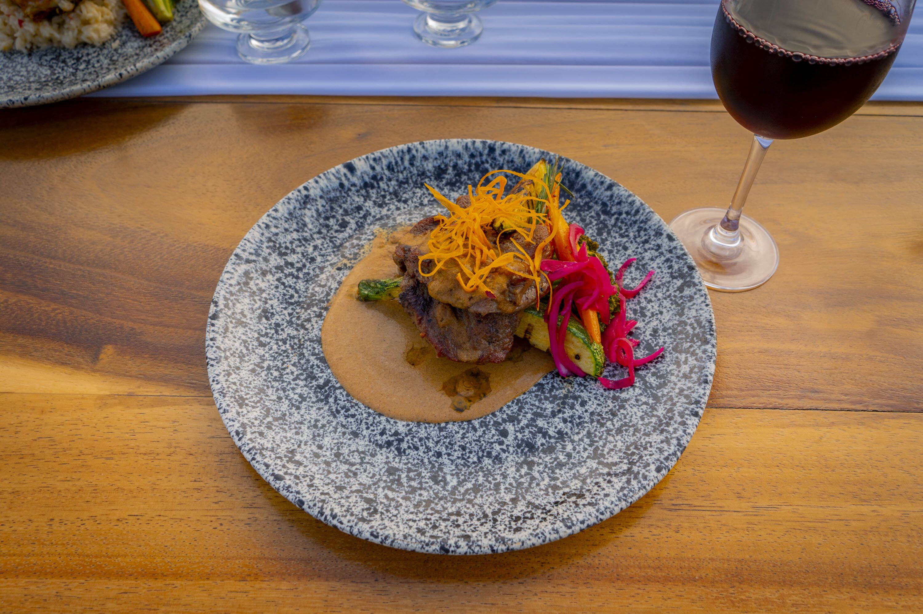 A plate of food with a glass of red wine on a wooden table.