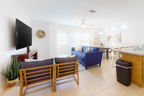 A living room with a TV, sofa, chairs, and a small dining area. - Lovely Townhome w/Shared Pool, Central AC, WiFi - Short Walk to Beach (South Padre Island)