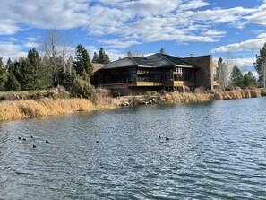 A lodge by a lake with a large building featuring multiple windows and a balcony. - Pet Friendly Villa Unit with Two-Primary Bedroom Suites on Bend's Westside (Bend)