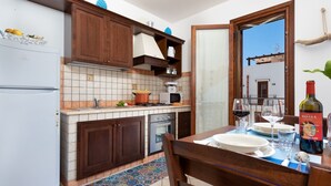 A kitchen with wooden cabinets, a tiled backsplash, a stove, and a dining area with a table set for two.