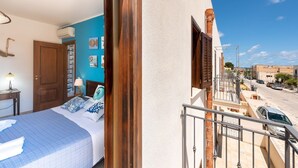 A bedroom with a bed, bedside table, and a view of the street.
