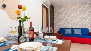 A dining table set with plates, glasses, cutlery, and bottles of wine. There is a blue sofa in the background.