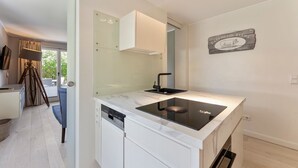 A modern kitchen with a glass door, a black induction cooktop, and a white cabinet. - The Villa 1903, Whg. 4 - The Villa 1903 (Sylt)