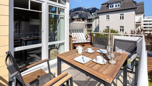 An outdoor dining area with a table set for two, a chair, and a sofa. - Residence Bismarck, Whg. 9 - Residence Bismarck (Sylt)