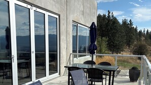 Une terrasse aménagée avec du mobilier d’extérieur, notamment des chaises et des tables, située près d’un bâtiment doté de grandes fenêtres et d’une façade en béton.