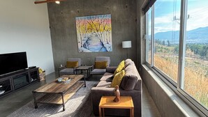 Un salon spacieux avec une grande fenêtre, un tableau au mur et un canapé moderne.