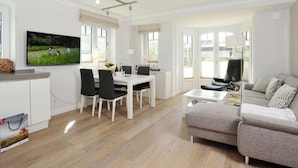 Un salon moderne comprenant un coin repas, un canapé et un téléviseur.
