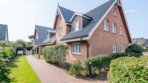 Une rangée de maisons modernes en briques, dotées de toits à forte pente et d’un jardin agrémenté d’un chemin bien entretenu.