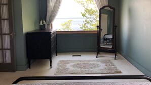 Une chambre avec une fenêtre, une commode, un miroir et un lit.