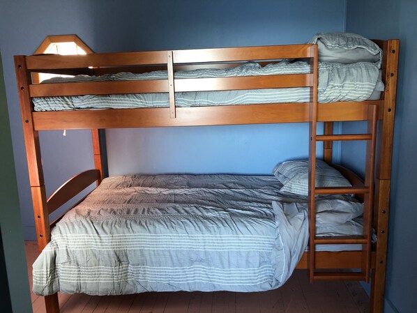 A bunk bed with a wooden frame and a grey striped bedspread.