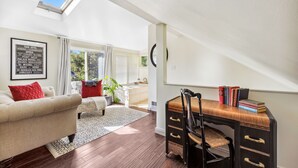 A room with a skylight, a desk with books, a sofa, and a framed sign on the wall. - Peak House Hot Tub 3BR 2.5BA Close to Downtown  (Boise)