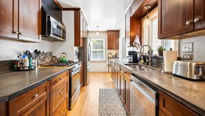 A modern kitchen with wooden cabinets, stainless steel appliances, and a granite countertop. - Peak House Hot Tub 3BR 2.5BA Close to Downtown  (Boise)