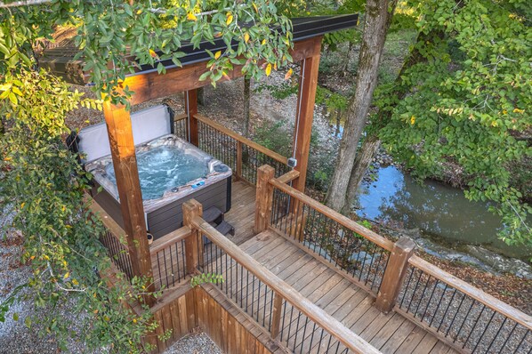 Un bain à remous sur une terrasse en bois, avec vue sur une rivière.
