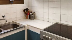 A kitchen with a stainless steel sink, a stovetop oven, and a window with a curtain. - Lovely apartment for 4 people with WIFI, TV and terrace (Sant Feliu De Guíxols)