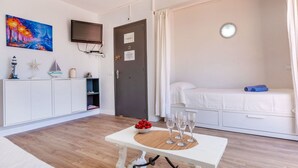 A room with a bed, a table with glasses, a TV, and a painting on the wall. - Lovely apartment for 4 people with WIFI, TV and terrace (Sant Feliu De Guíxols)