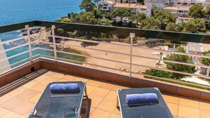 A balcony with two sun loungers, a view of the sea, and a coastal town in the background. - Lovely apartment for 4 people with WIFI, TV and terrace (Sant Feliu De Guíxols)
