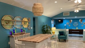 Cozinha moderna com ilha de madeira, banquetas brancas e uma parede em tom de verde-água.