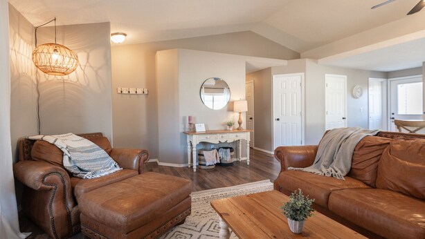 A living room with leather sofas, a wooden coffee table, a patterned rug, a white console table, and a hanging light fixture.