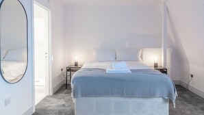 A bedroom with a bed, two bedside lamps, a mirror, and a door. - Newly Refurbished 2 bed with Fantastic View (London)