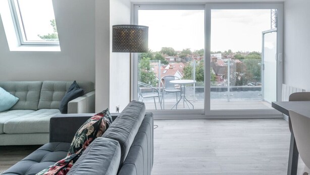 A modern living room with a sofa, a patterned throw, and a dining area with a table and chairs. - Newly Refurbished 2 bed with Fantastic View (London)