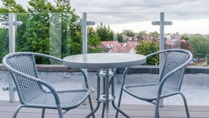 A balcony with two wicker chairs and a round table, overlooking a residential area. - Newly Refurbished 2 bed with Fantastic View (London)