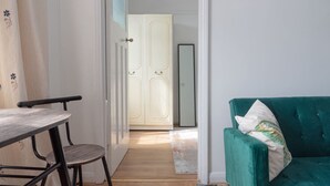 Um quarto com um sofá azul-turquesa, uma mesa de madeira e uma porta branca que dá para outro cômodo.
