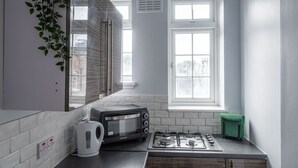Cozinha compacta com torradeira, chaleira e fogão a gás, uma janela e uma planta.