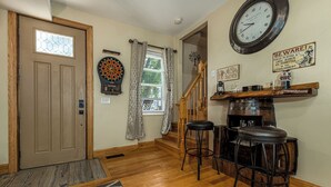 A room with a dartboard, a clock, a bar area with stools, and a staircase. - Amazing! 2 Bed Townhouse in the HEART of Dbq! (Dubuque)
