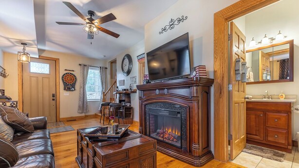 A living room with a fireplace, a television, and a clock on the wall. - Amazing! 2 Bed Townhouse in the HEART of Dbq! (Dubuque)