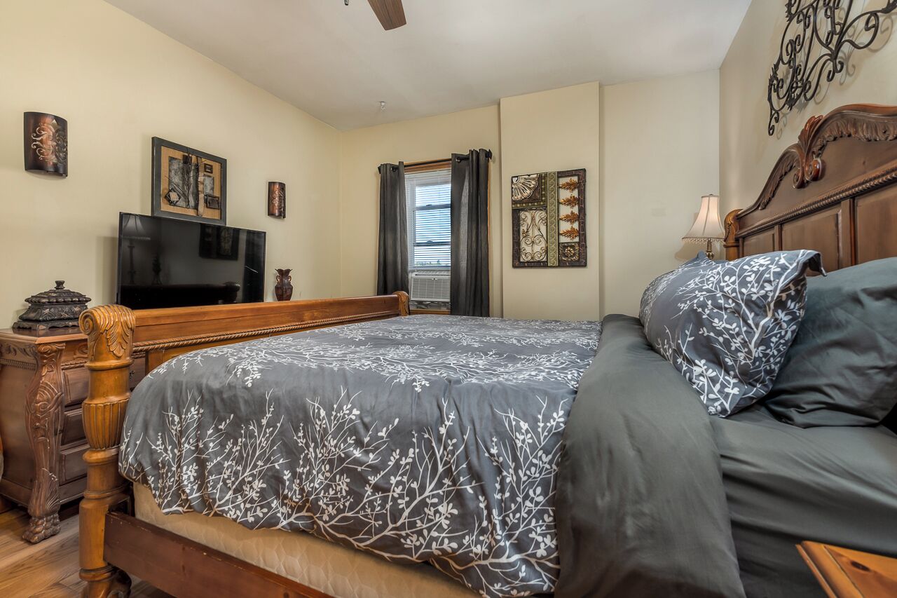 Een slaapkamer met een houten bed, een televisie en kunstwerken aan de wanden.