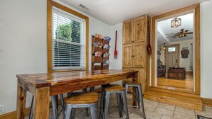 A kitchen with a wooden table and bar stools, a bookcase, and wooden cabinets. - Amazing! 2 Bed Townhouse in the HEART of Dbq! (Dubuque)