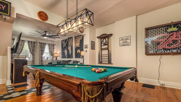 A pool table with a green felt surface, surrounded by wooden flooring and decorative rope tassels. - Majestic & Relaxing Home w/ 3 Beds Pool Table Bar! Sleeps 8 (Dubuque)