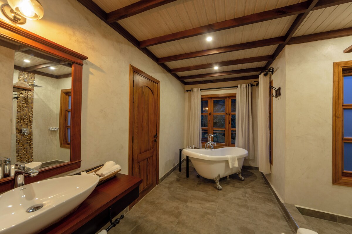 Un baño con un lavabo grande, una bañera independiente, un espejo y una ventana con cortinas.