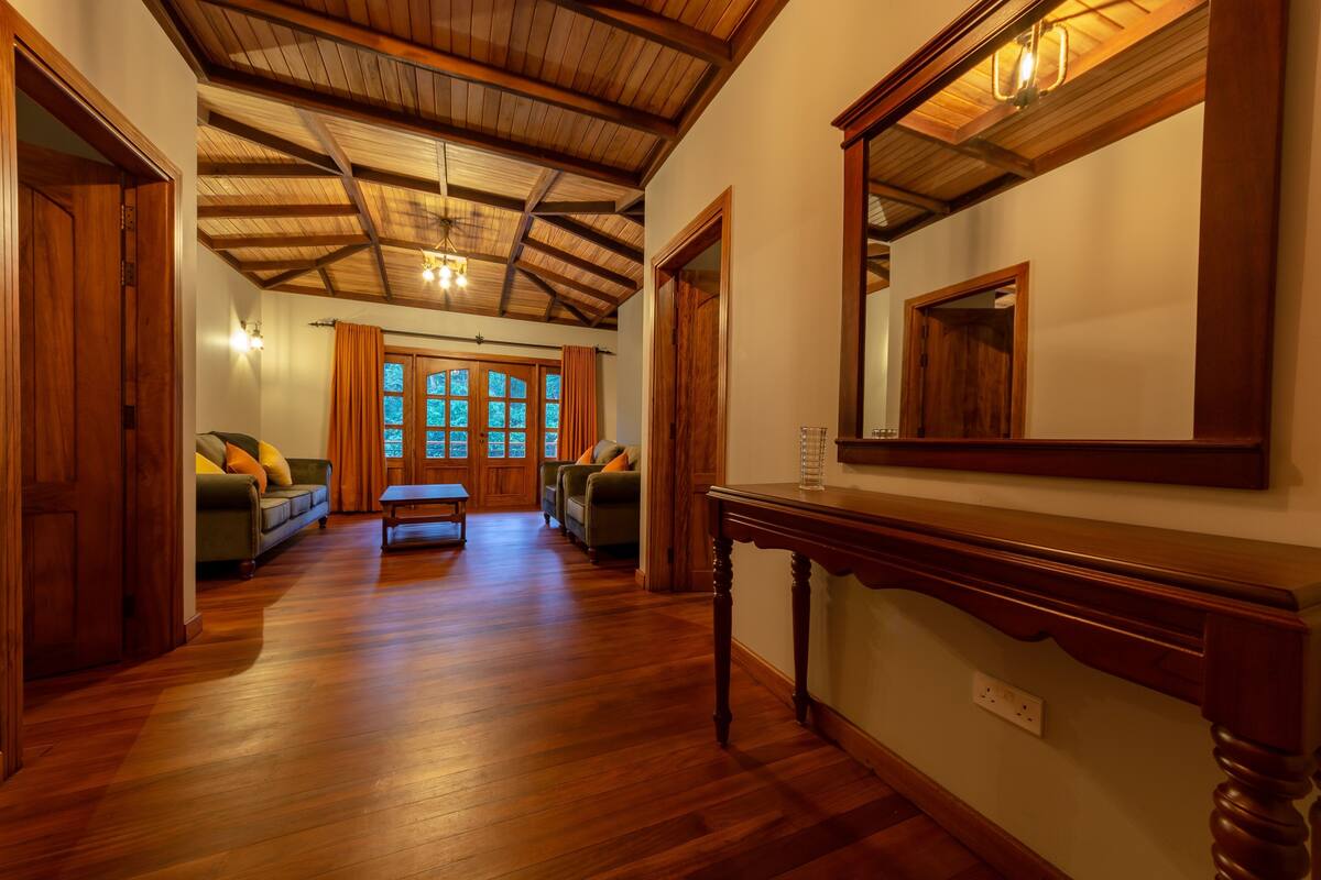 A hallway with wooden flooring, a bench, and a large mirror on the wall.