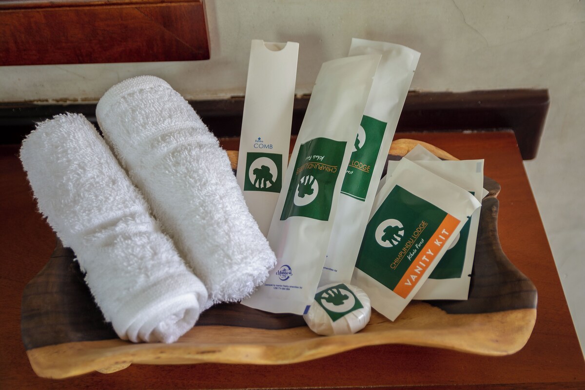 A wooden tray with a white towel, a comb, and several hygiene products.