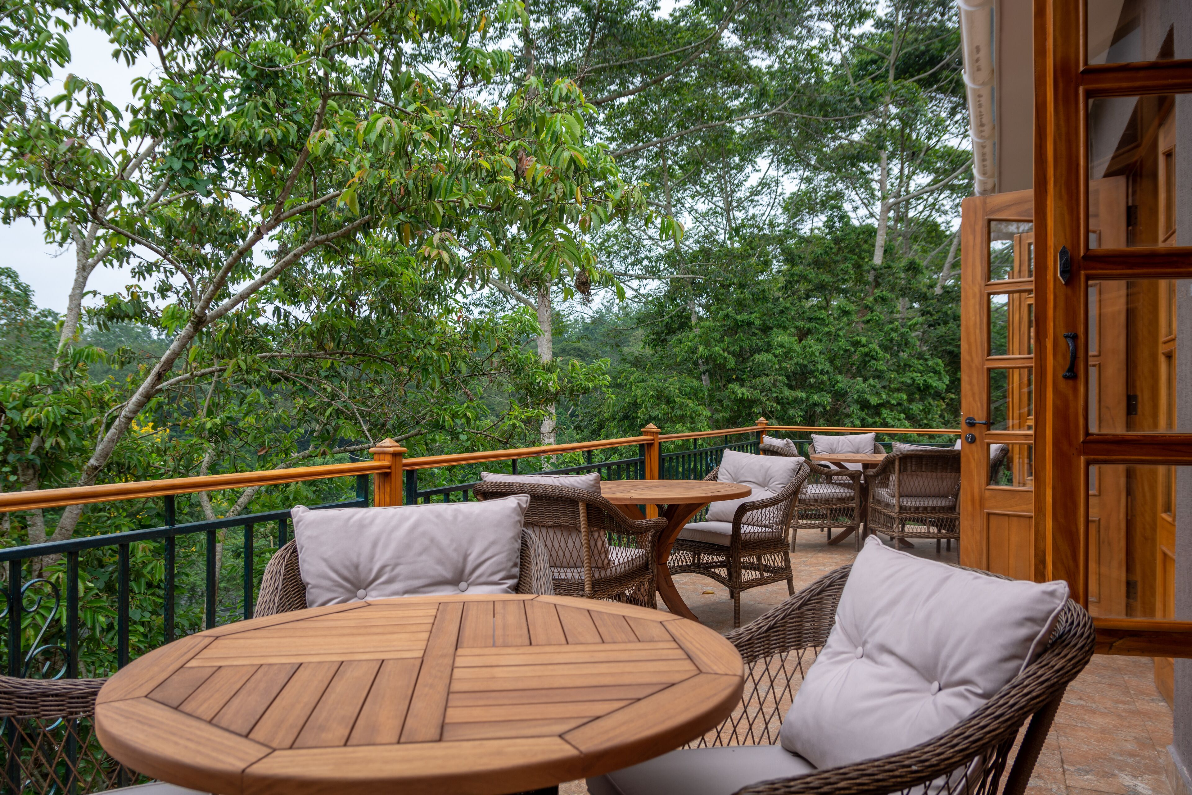 Una terraza de madera con mobiliario de mimbre y vistas a vegetación exuberante.