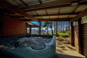 Een hottub onder een houten pergola, met uitzicht op bomen en bergen.