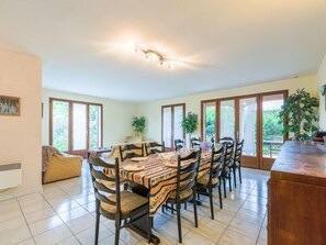 A dining area with a long table, chairs, and a wooden cabinet.