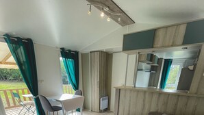 A modern living room with a sectional sofa, a small table, and a dining area with chairs. - Charming mobile home in the heart of nature (Vidauban)