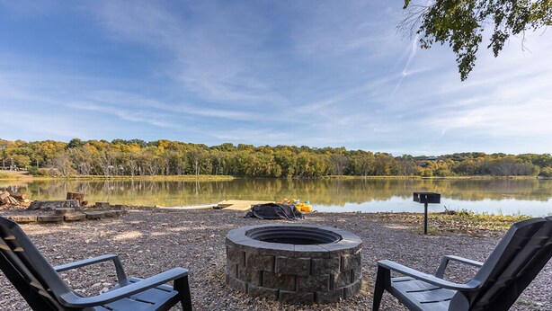 A lakeside setting with two chairs and a fire pit.
