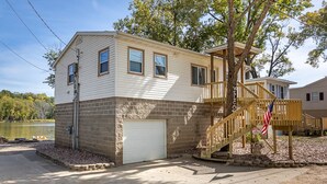 A two-story house with a garage, a wooden staircase, and an American flag.